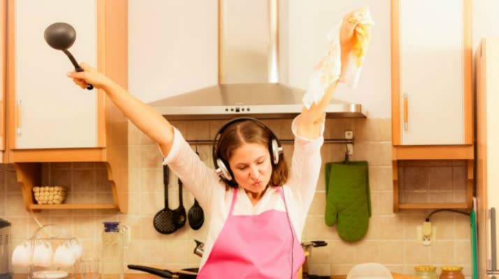 Cooking preparing and making food concept. Modern beauty woman housewife cook chef wearing pink apron listening music on earphones singing and dancing in kitchen.